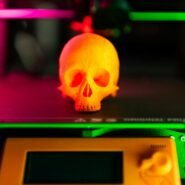 Crâne orange imprimé en 3D sur une imprimante avec des lumières colorées