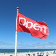 Drapeau rouge avec le mot 'Open' flottant sur une plage