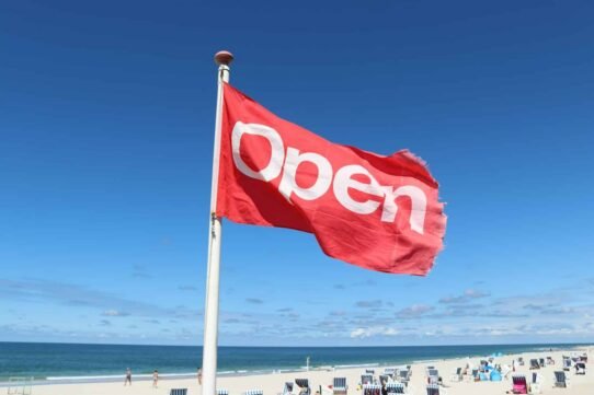 Drapeau rouge avec le mot 'Open' flottant sur une plage