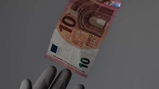 Deux mains gantées échangent un billet de dix euros