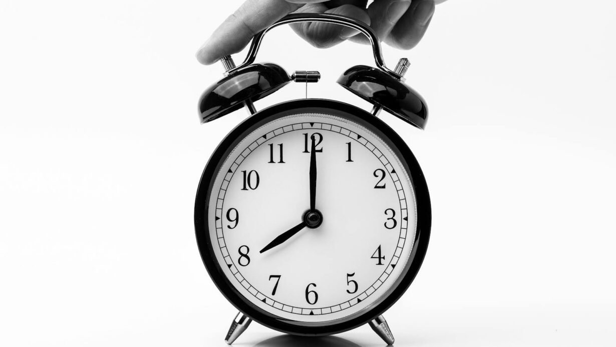 Réveil mécanique noir avec une main réglant l'heure