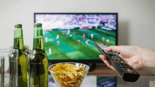 Personne regardant un match de football avec des bières et des chips