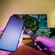 Smartphone et télécommande devant un écran de télévision