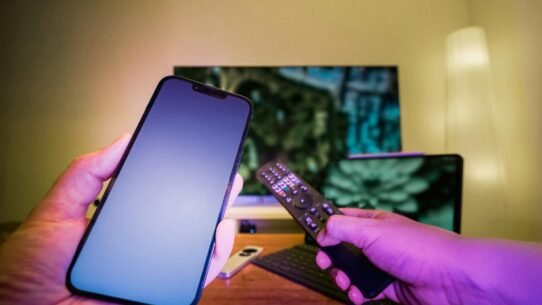Smartphone et télécommande devant un écran de télévision