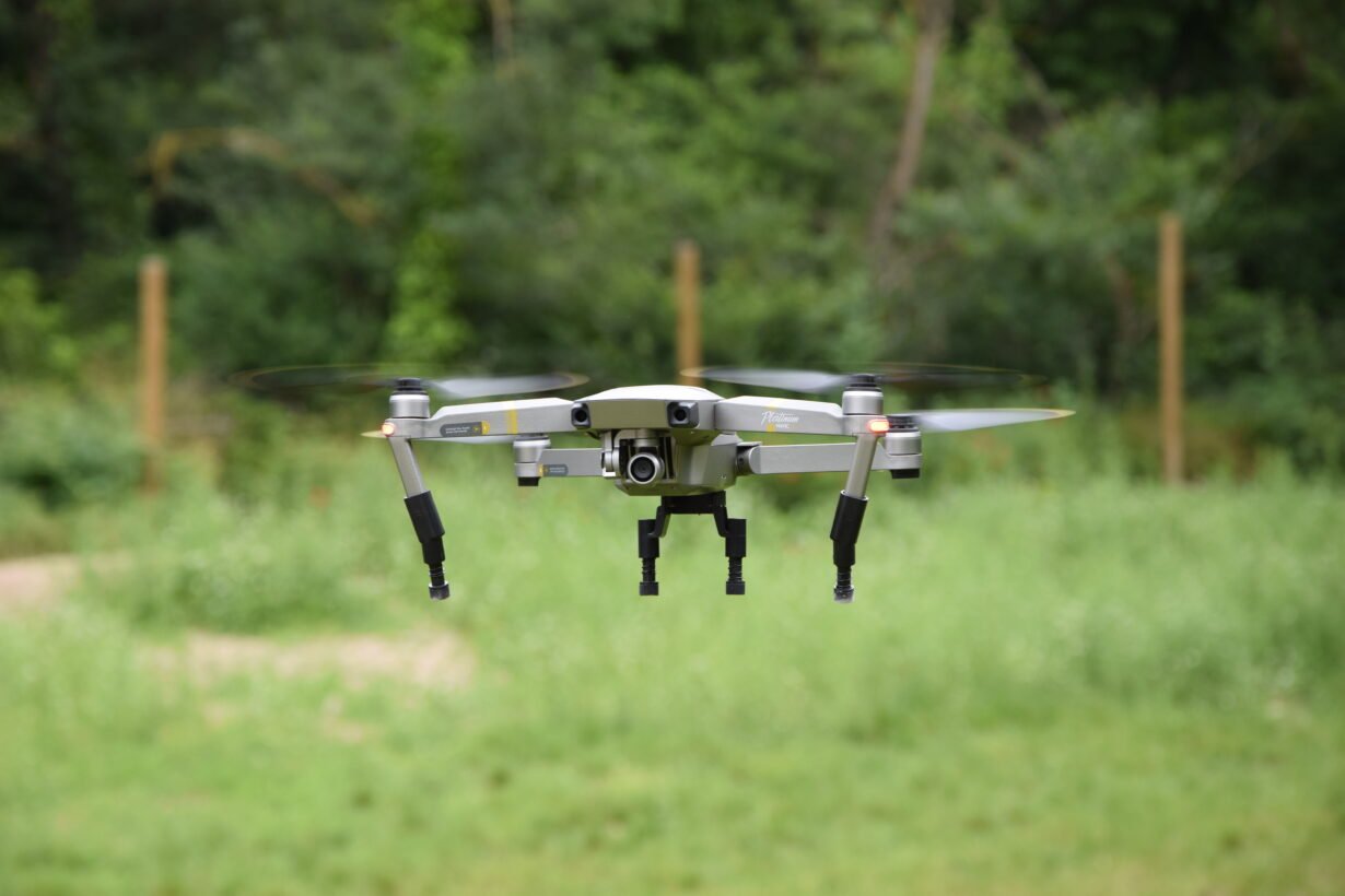 Drone en vol stationnaire devant un fond de nature verdoyante