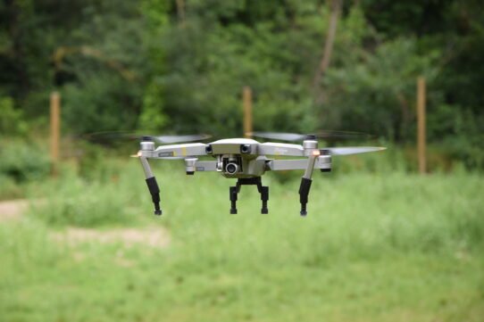 Drone en vol stationnaire devant un fond de nature verdoyante