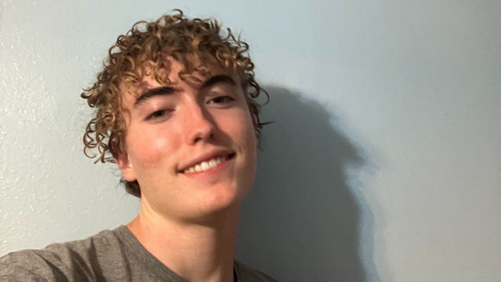 Jeune homme avec des cheveux bouclés souriant