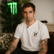 Homme tatoué en t-shirt blanc assis sur un canapé