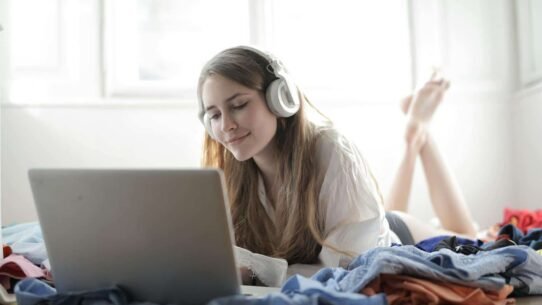 Femme allongée avec un casque écoutant de la musique sur un ordinateur