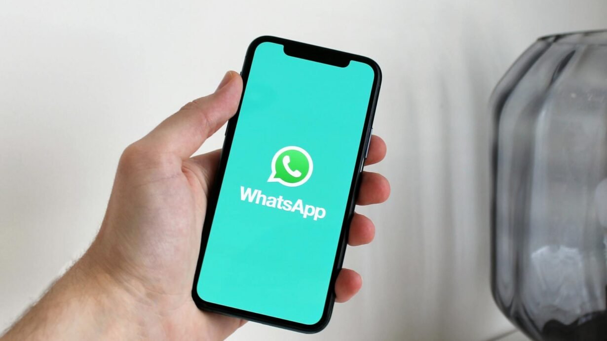 Main tenant un smartphone avec l'application WhatsApp ouverte