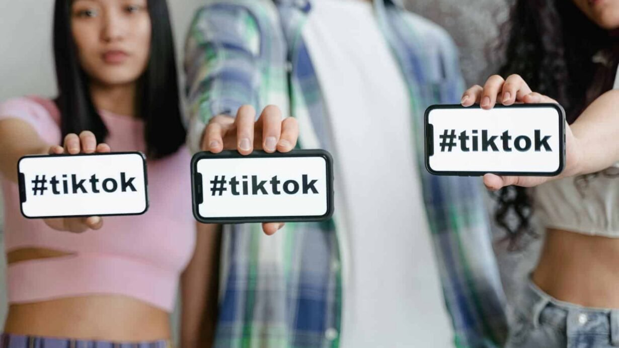 Trois personnes montrant des téléphones avec le hashtag TikTok