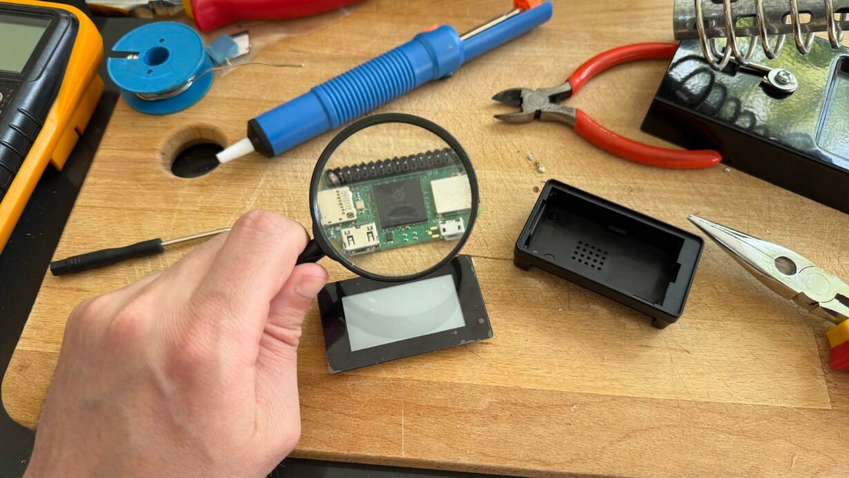 Main tenant une loupe au-dessus d'un circuit imprimé sur un établi