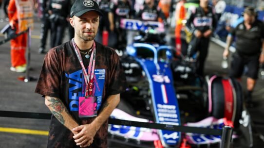 Homme avec un badge VIP devant une voiture de course floue