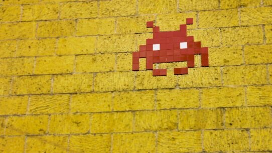 Street art en mosaïque rouge sur mur de briques jaunes
