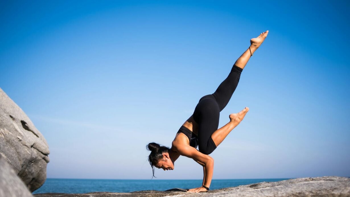 Personne en posture de yoga sur un rocher avec vue sur la mer