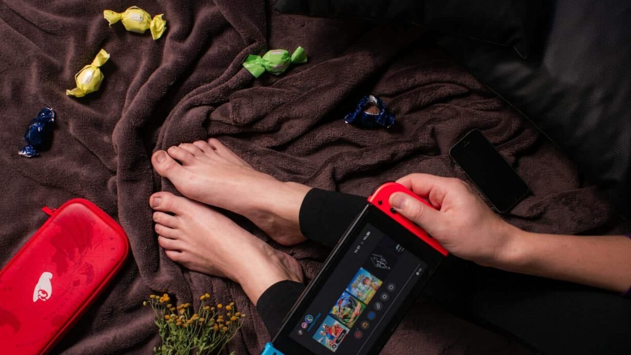 Personne tenant une console de jeu portable sur une couverture