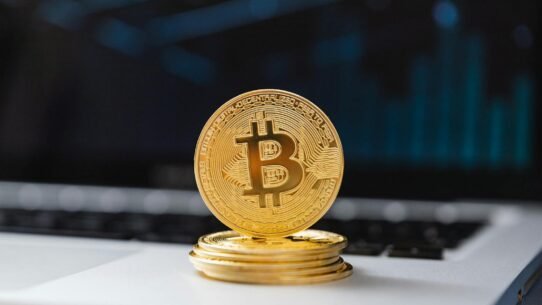 Pièce de Bitcoin dorée posée sur un ordinateur portable