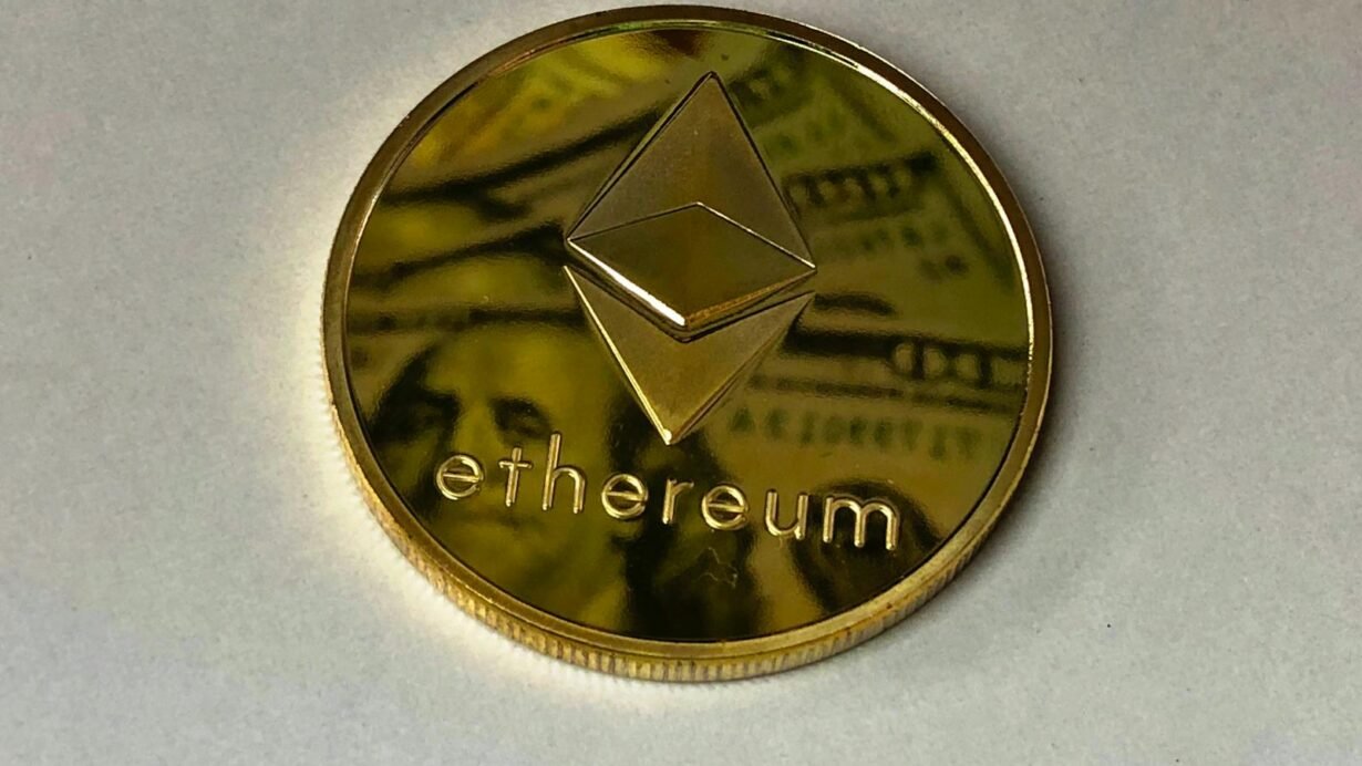 Pièce Ethereum dorée posée sur un billet de banque