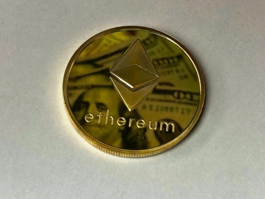 Pièce Ethereum dorée posée sur un billet de banque