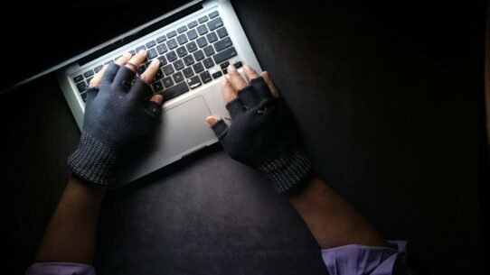 Mains avec gants sur un clavier d'ordinateur portable