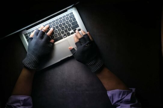 Mains avec gants sur un clavier d'ordinateur portable