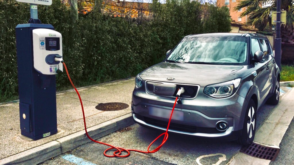 Voiture électrique grise branchée à une borne de recharge en extérieur